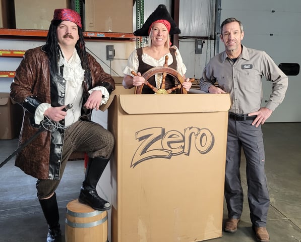 Two people dressed up like pirates and a third dressed in a warehouse work uniform pretending a Helluva Gaylord Box is a ship