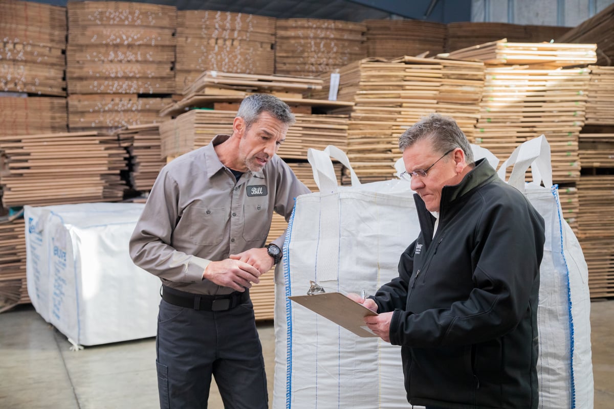 Two men in a warehouse looking at a clipboard