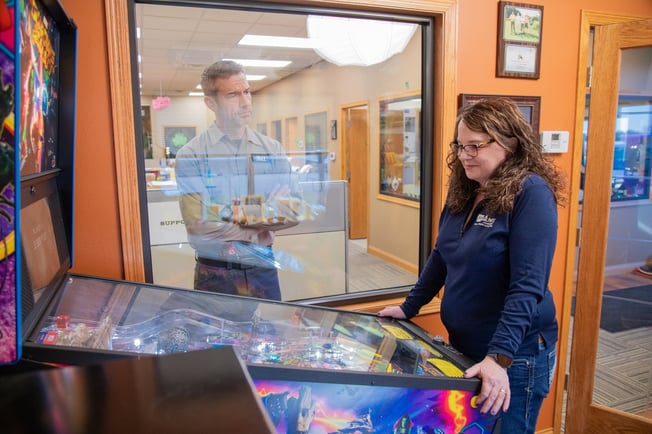 Man watching a woman play pinball