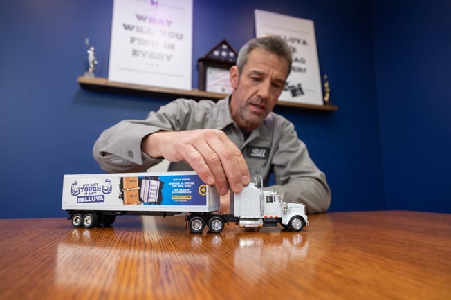 Man playing with a toy semi truck with a helluva wrap around the trailer