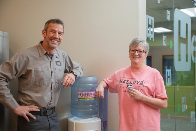 Man and woman standing next to the water cooler and smiling for the camera